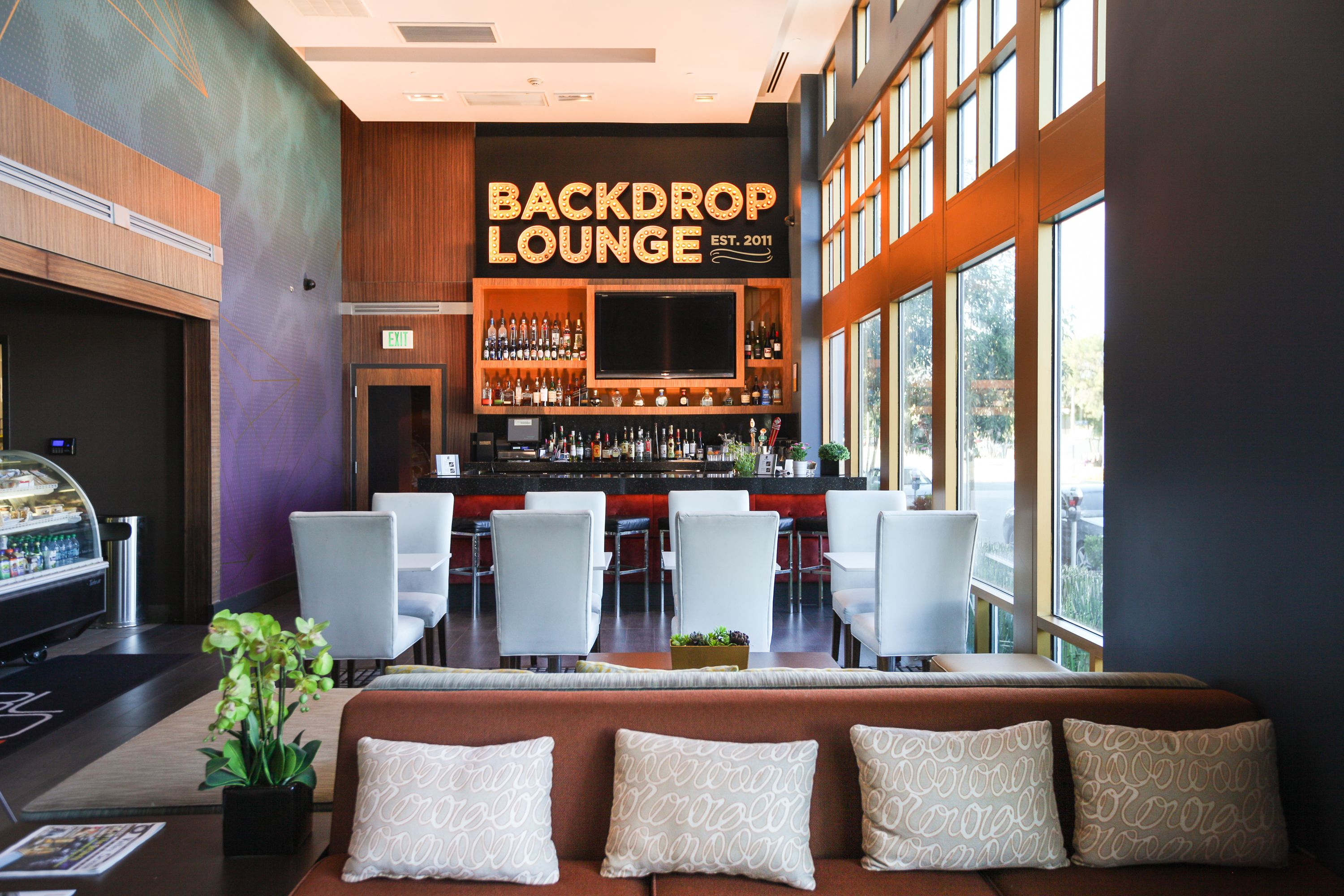 A modern lounge with a bar, seating area, and a large screen.