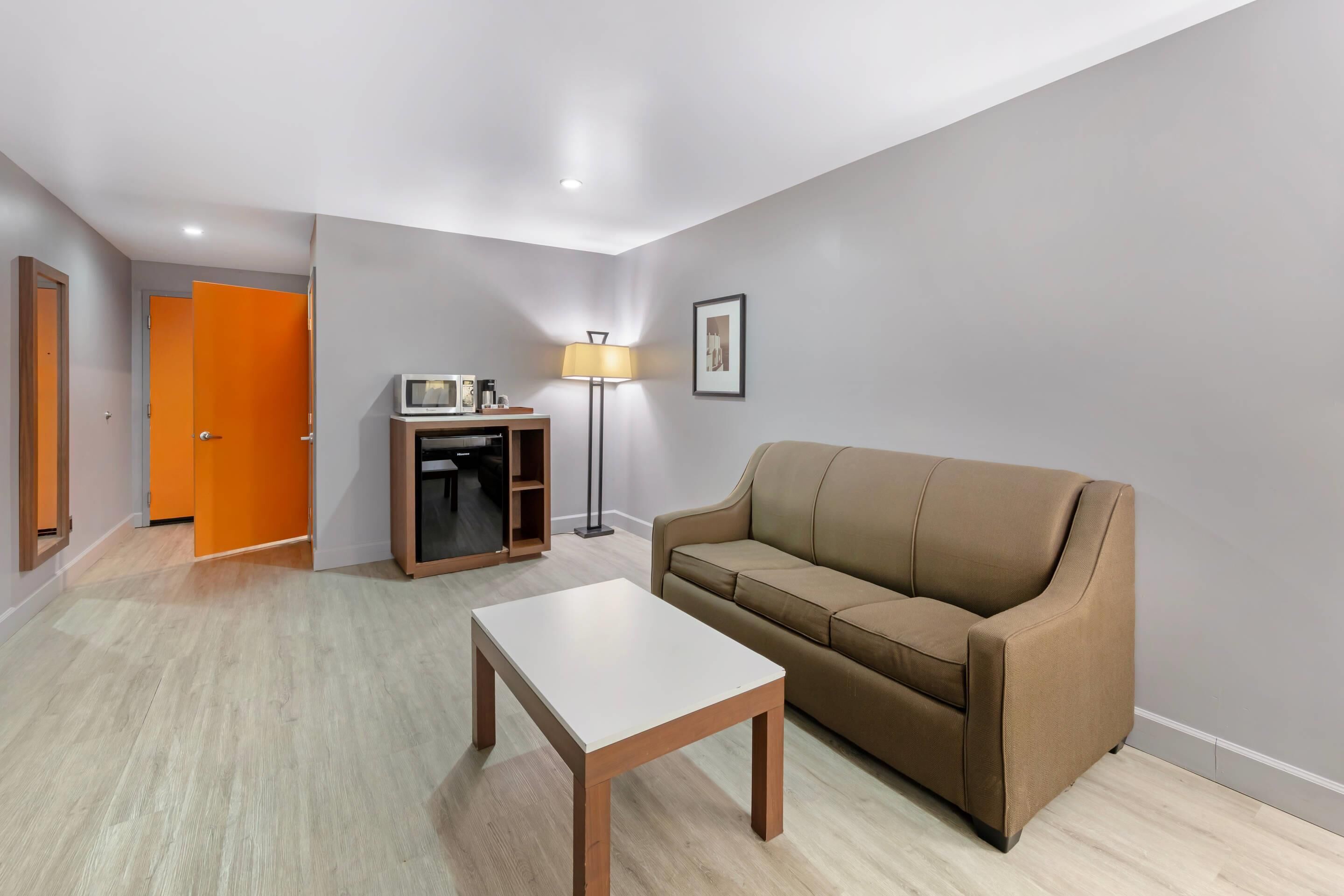 A modern living room with a beige sofa, a white coffee table, a floor lamp, and a small entertainment unit.