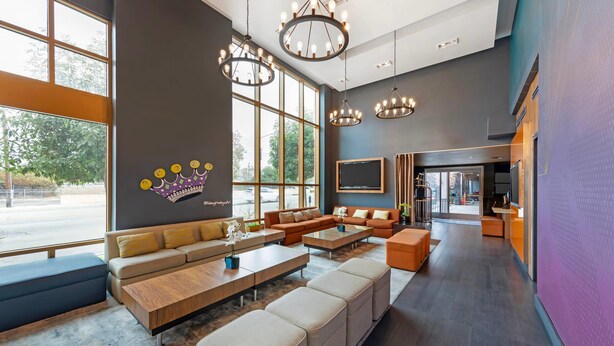 A spacious lobby with a large seating area, modern chandeliers, and large windows offering a view of the outdoors. - BLVD Hotel and Studios Universal-Hollywood, an Ascend Collection Hotel (Studio City)