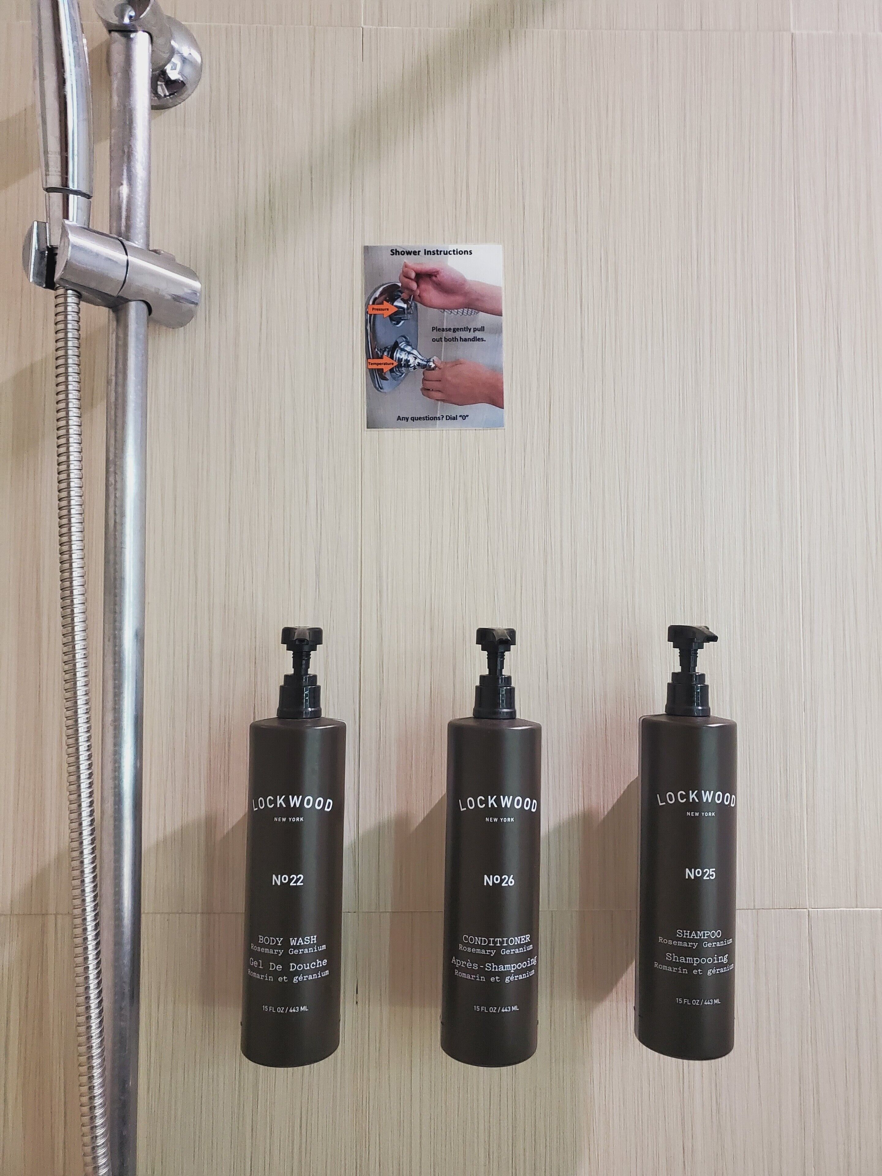 A shower with a hand-drawn instruction sign, and three Lockwood New York toiletries on the wall.