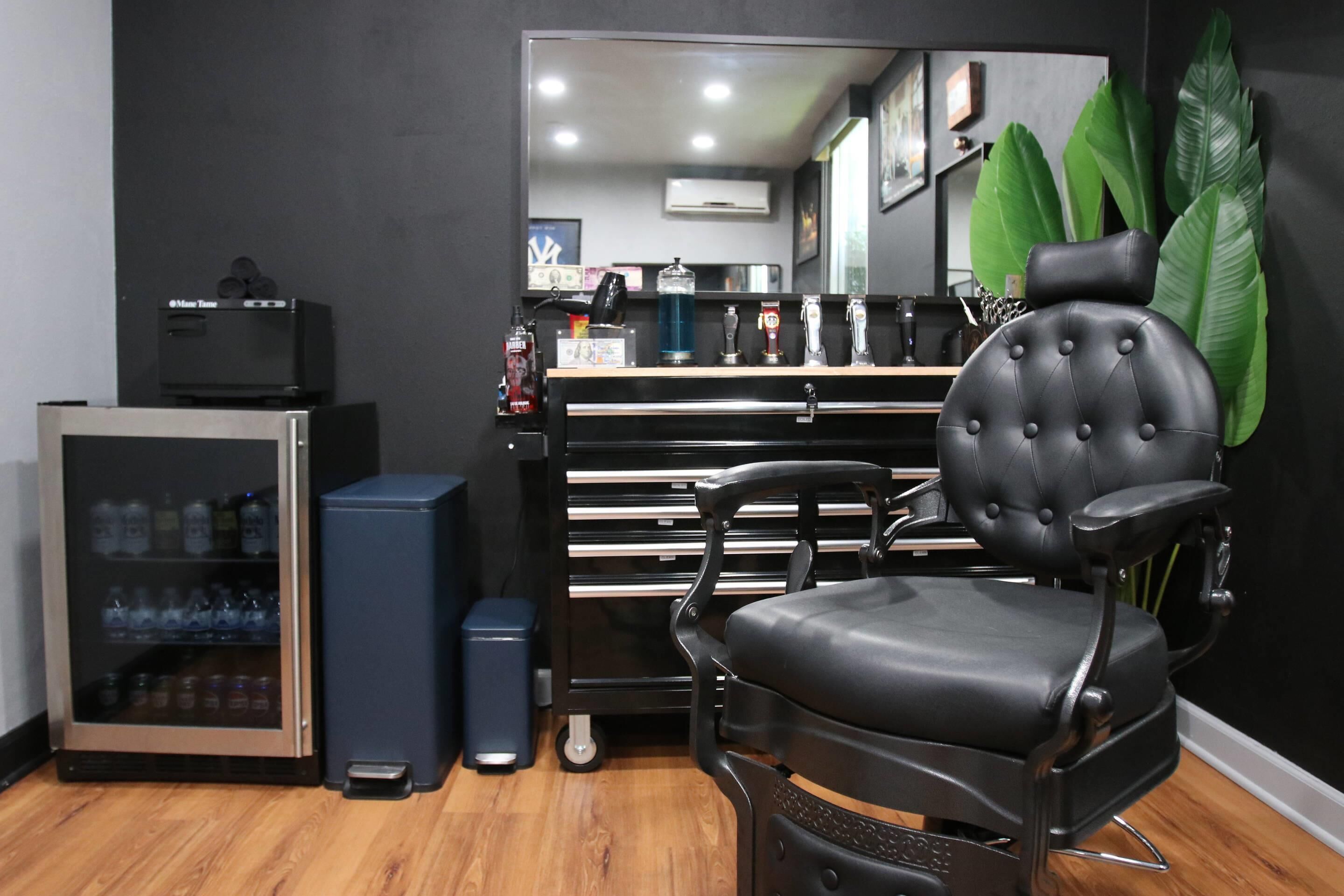 A modern room with a black leather chair, a minibar, and a large mirror.