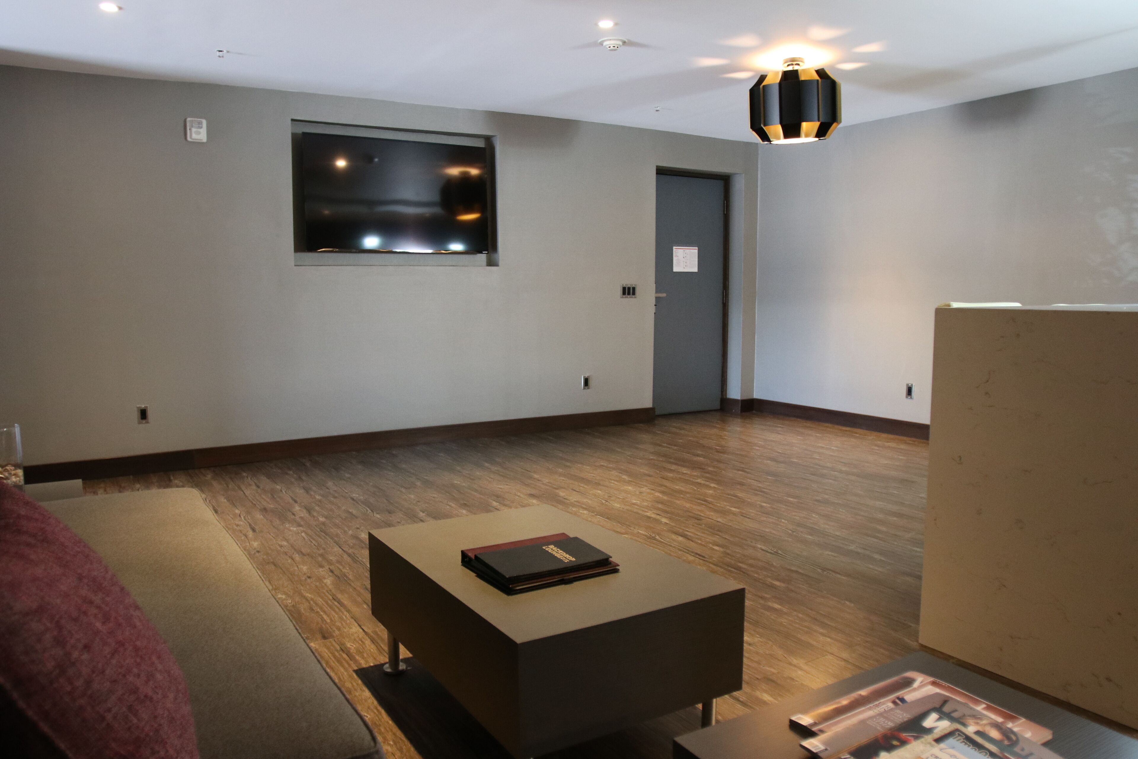 A modern room with a wooden floor, a sofa, a coffee table, a window, and a door.