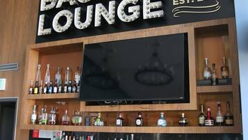 A bar area with a large sign reading "BACKDROP LOUNGE EST. 2011" and a TV mounted above the bar.