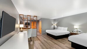 A hotel room with a large bed, a smaller bed, a desk with a chair, a TV, and a bathroom visible through a door. - BLVD Hotel and Studios Universal-Hollywood, an Ascend Collection Hotel (Studio City)