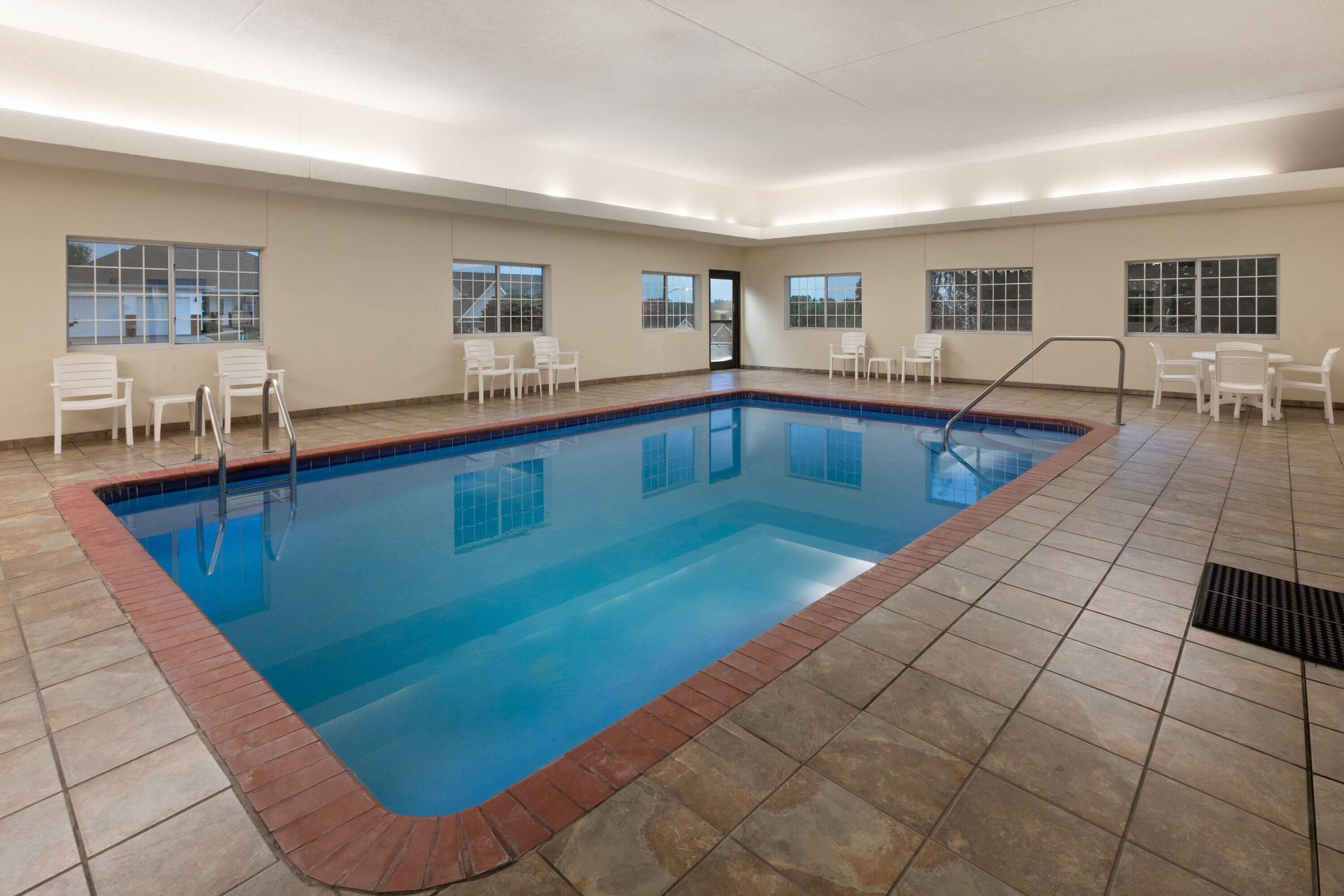 A rectangular indoor swimming pool with a tiled floor and a brick border.