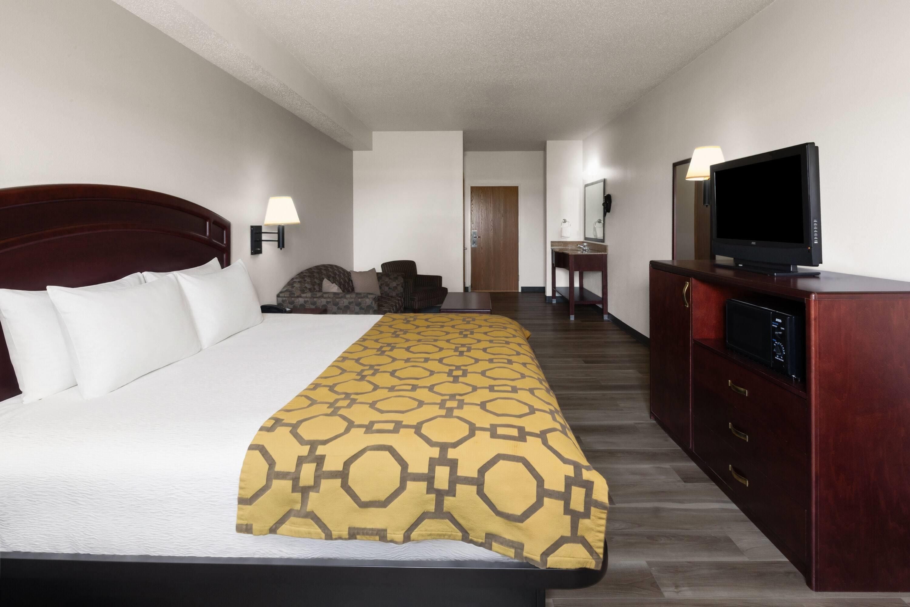 A hotel room with a bed, a TV, a desk, and a chair.