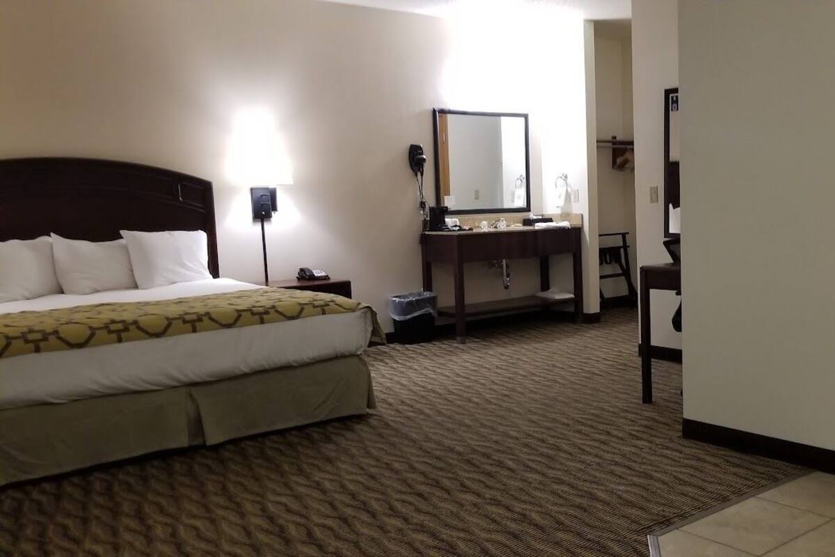 A hotel room with a bed, a desk with a mirror, a sink, and a bathtub.