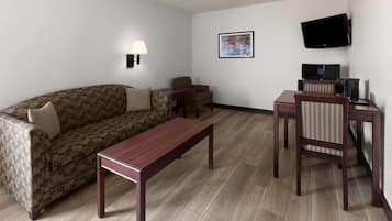 Una sala de estar amoblada con un sofá, una mesa de centro, un televisor y una pequeña mesa con una silla.