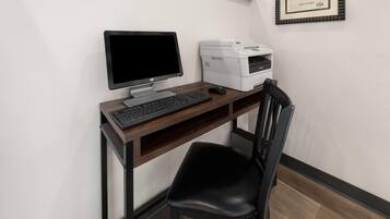 Un espacio de trabajo con computadora de escritorio, teclado, ratón e impresora sobre un escritorio de madera.