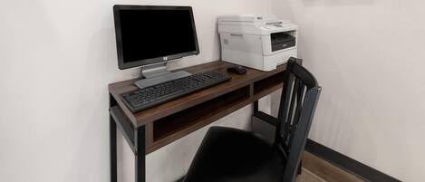 Un espacio de trabajo con computadora de escritorio, teclado, ratón e impresora sobre un escritorio de madera.