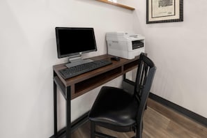 A workspace with a desktop computer, keyboard, mouse, and a printer on a wooden desk.