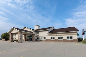 A two-story building with a covered entrance and a parking lot in front.