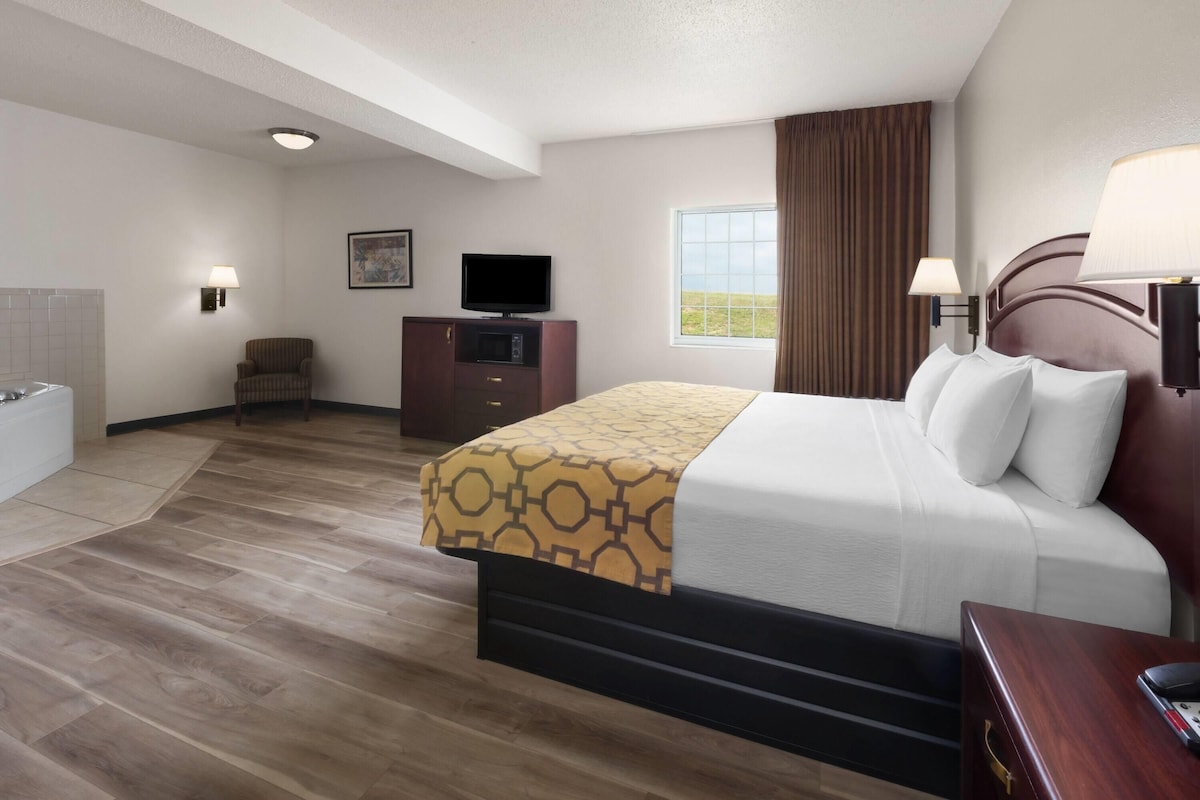 A hotel room with a bed, a television, a desk, and a bathroom.