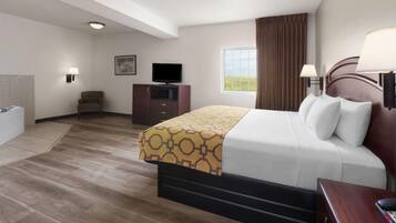 Ein Hotelzimmer mit Bett, Fernseher, Schreibtisch, Stuhl und einem Fenster mit Vorhängen.