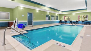 A swimming pool with a diving board, chairs, and a lifeguard chair.