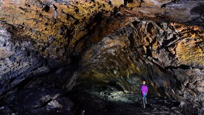 Una persona de pie en una cueva con paredes rugosas e irregulares y un estrecho pasadizo.