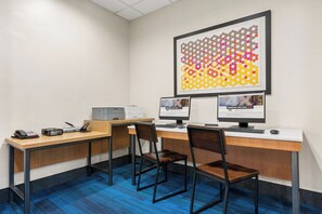 A modern office space with two desks, chairs, a printer, and a large abstract art piece on the wall.
