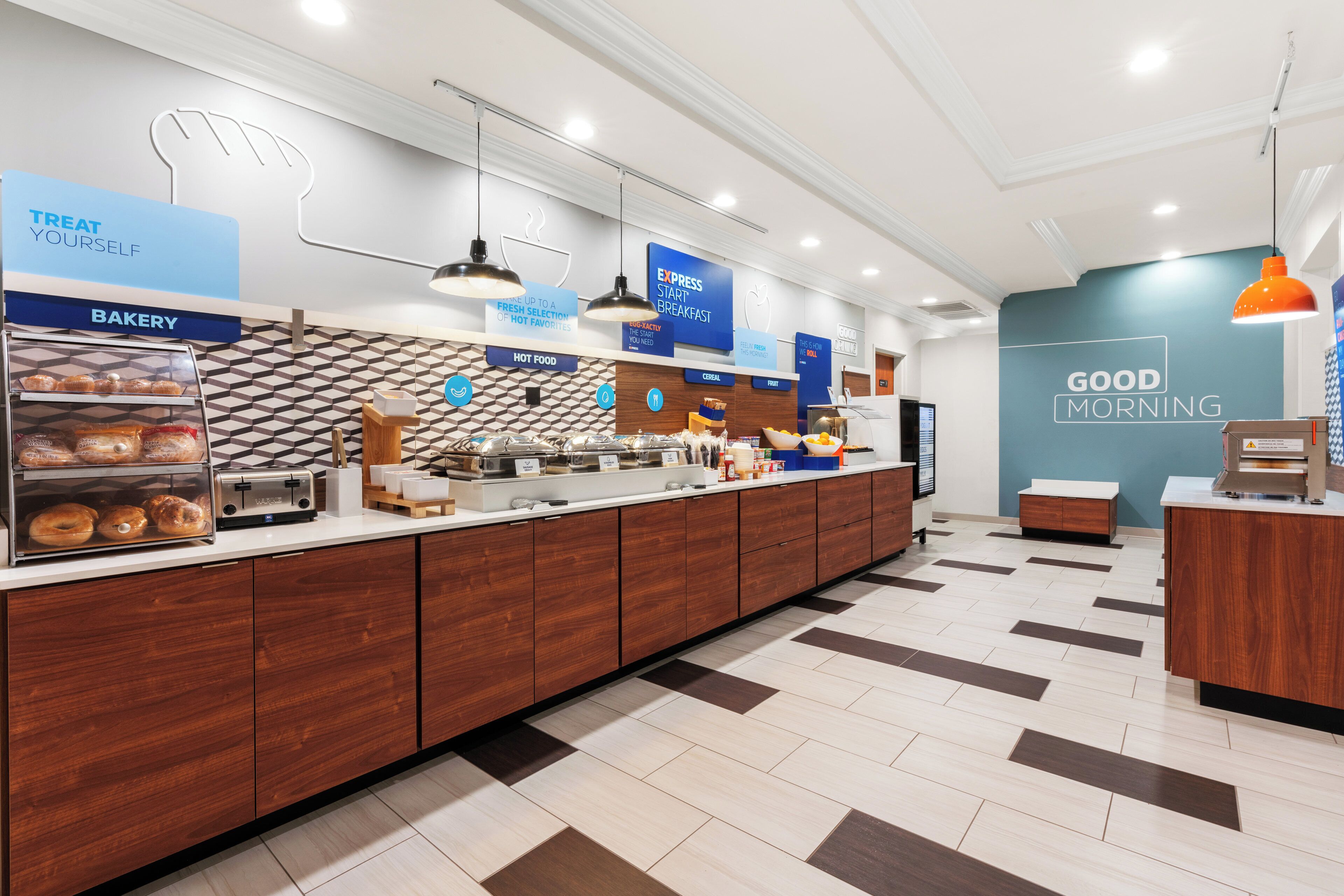 A modern breakfast area with a bakery section, a coffee station, and a sign that reads 'GOOD MORNING'.
