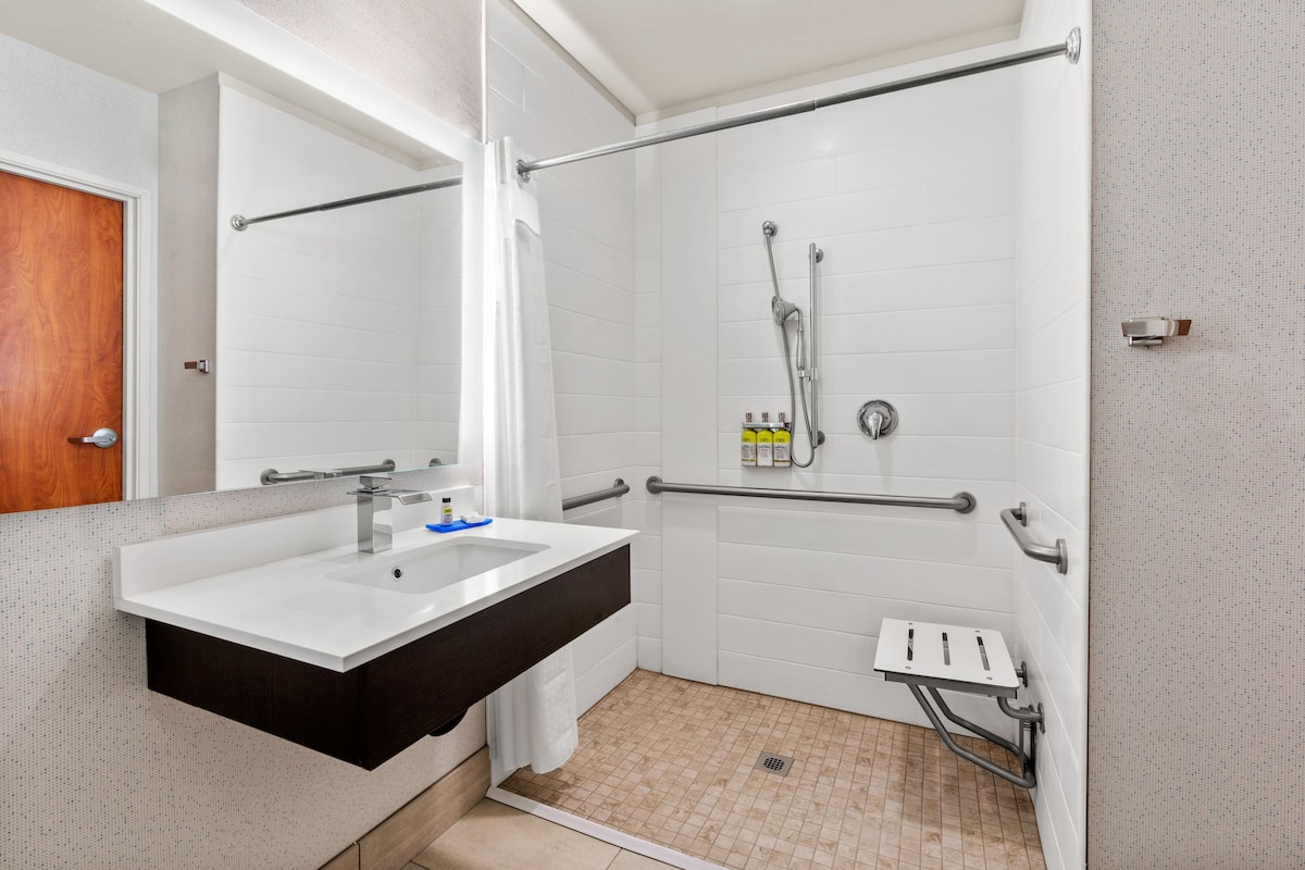 A bathroom with a white sink, mirror, and white tiled walls.