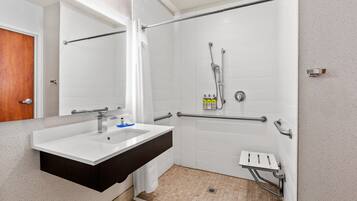 A bathroom with a white sink, mirror, and white tiled walls.