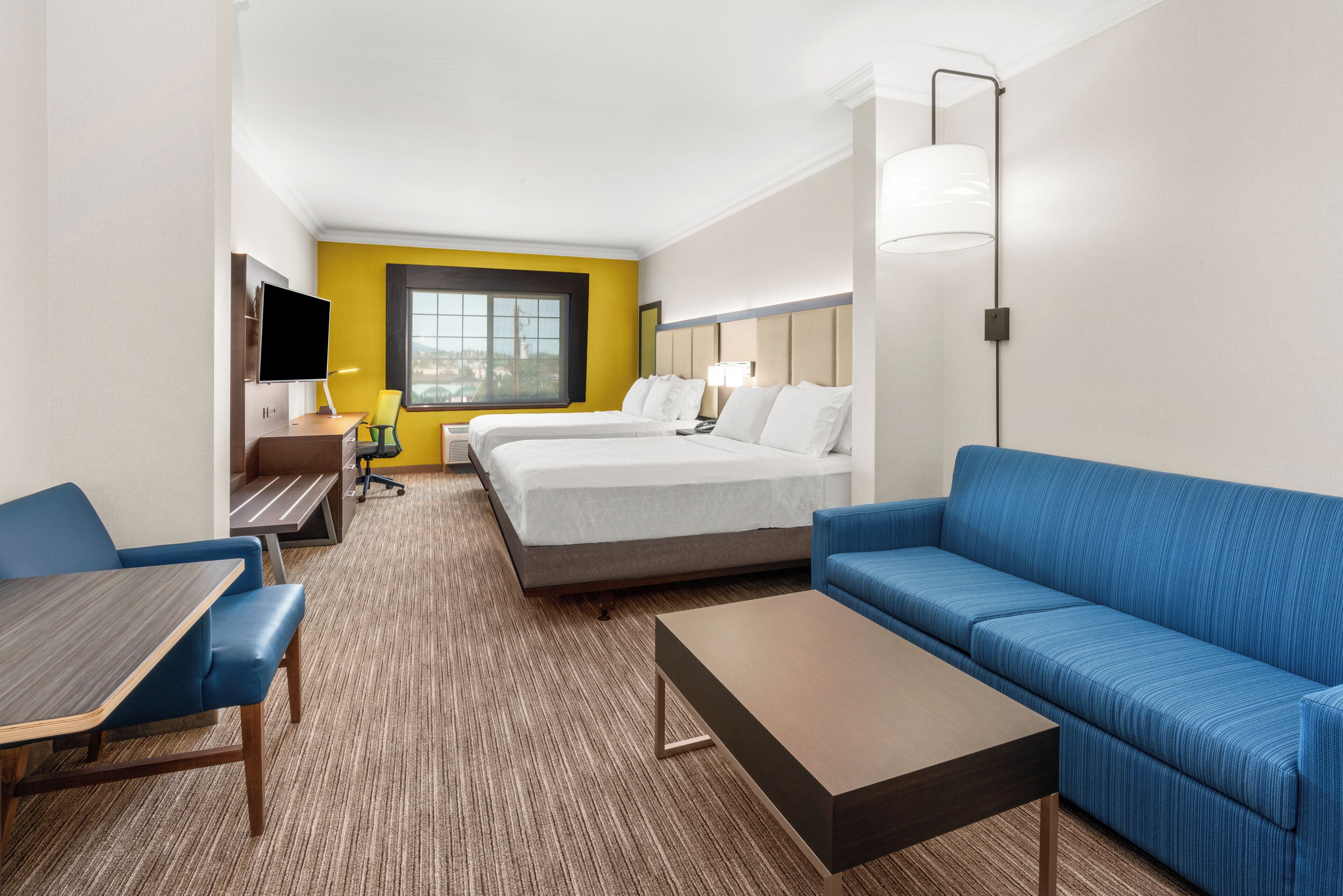 A hotel room with a bed, a sofa, a desk, and a TV.