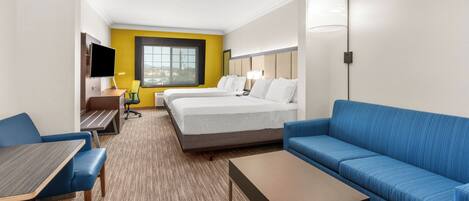 A hotel room with a bed, a sofa, a desk, and a TV.