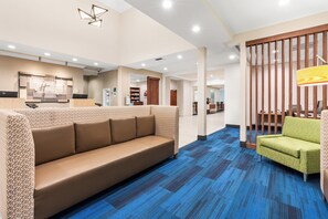 A hotel lobby with a sofa, a green chair, a reception desk, and a staircase. - Holiday Inn Express & Suites Klamath Falls Central by IHG (Klamath Falls)