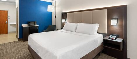 Una camera d'albergo con un letto grande, una scrivania con un computer, un telefono e una parete azzurra.