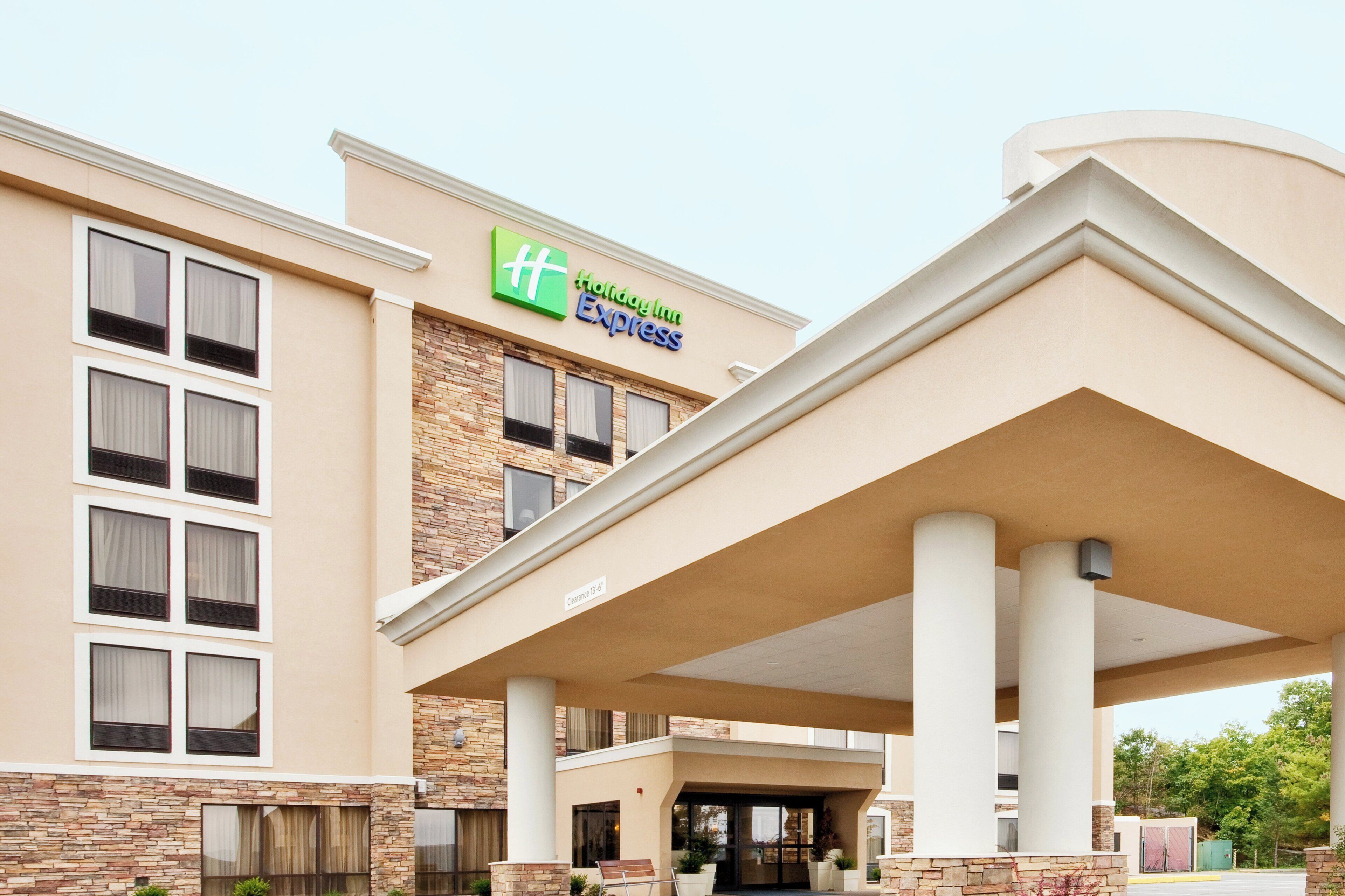 Ein Holiday Inn Express Gebäude mit Naturstein-Fassade, großen Fenstern und einem überdachten Eingangsbereich.