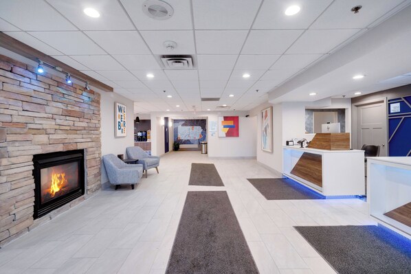 A modern lobby with a stone fireplace, seating area, reception desk, and a large map on the wall. - Holiday Inn Express Wilkes Barre East by IHG (Wilkes-Barre)