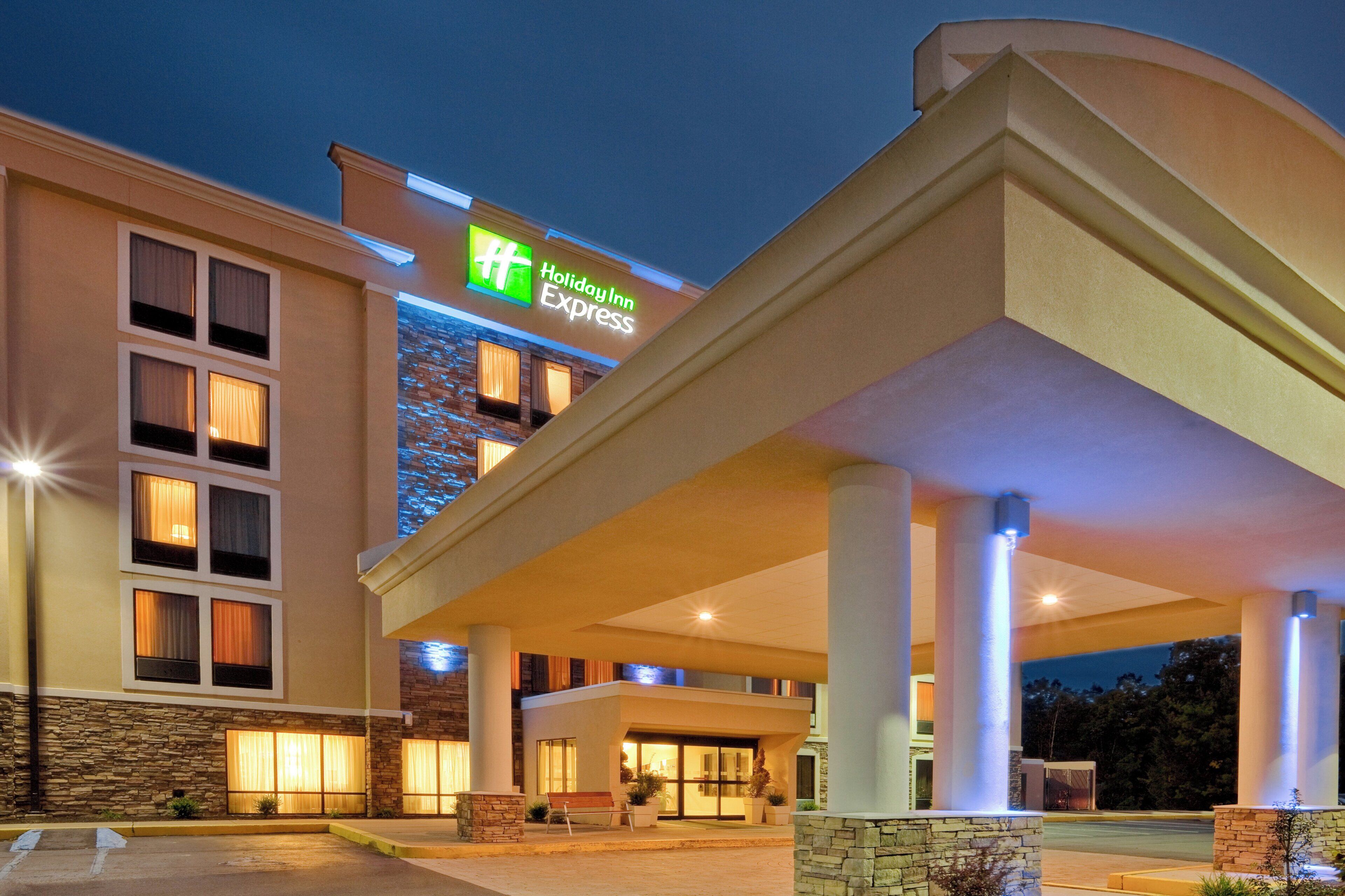 Ein Holiday Inn Express Gebäude mit einer Steinfassade, zahlreichen Fenstern und einem überdachten Eingangsbereich.