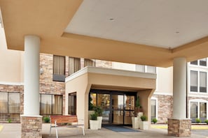 A building entrance with a covered patio, stone facade, and a bench. - Holiday Inn Express Wilkes Barre East by IHG (Wilkes-Barre)