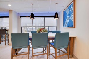 A conference room with a long table, three chairs, and two pendant lights.