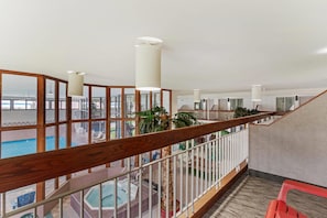 A hotel interior with a pool, a hot tub, and a wooden staircase.