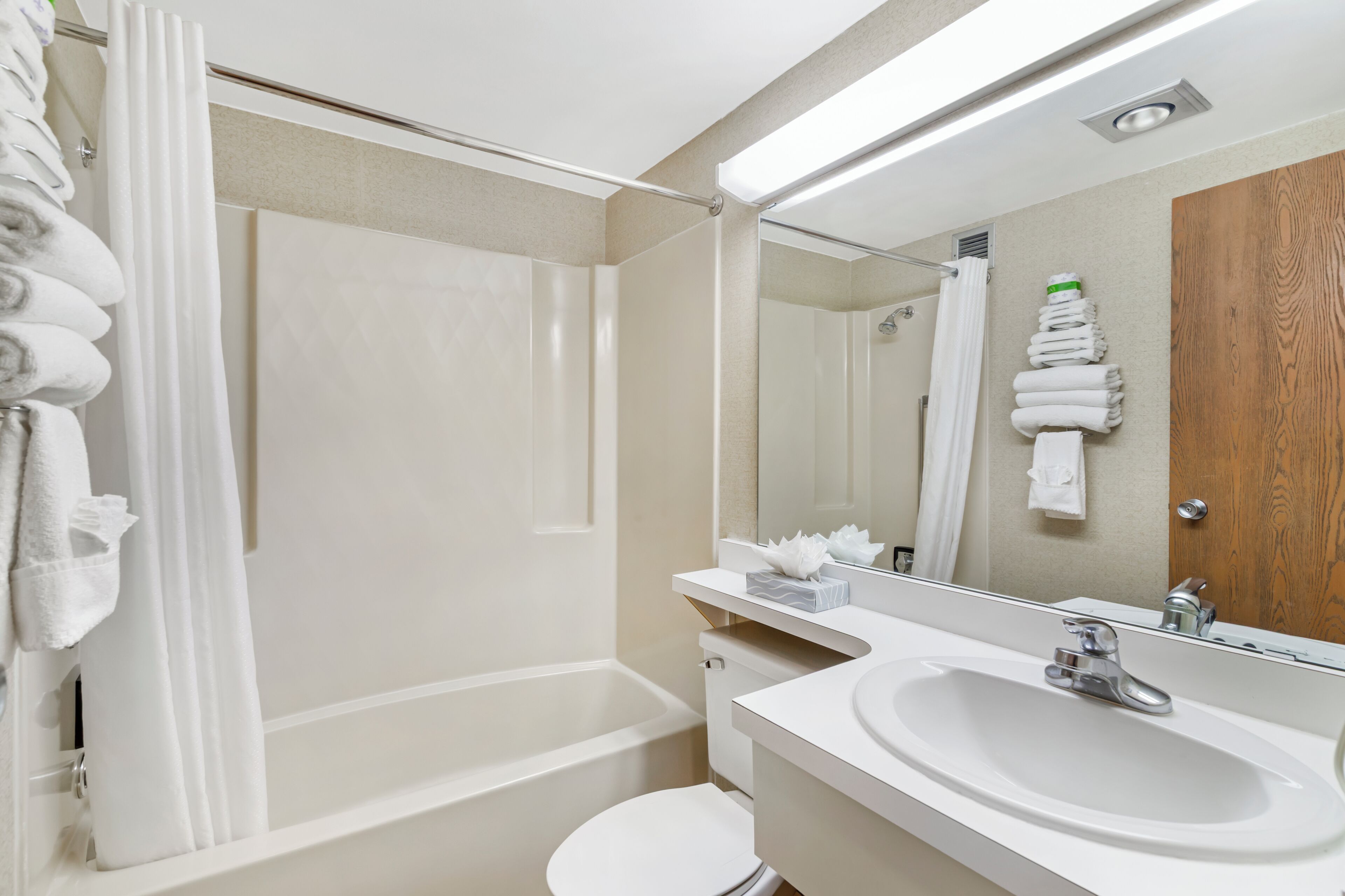 A bathroom with a bathtub, toilet, sink, and a mirror.