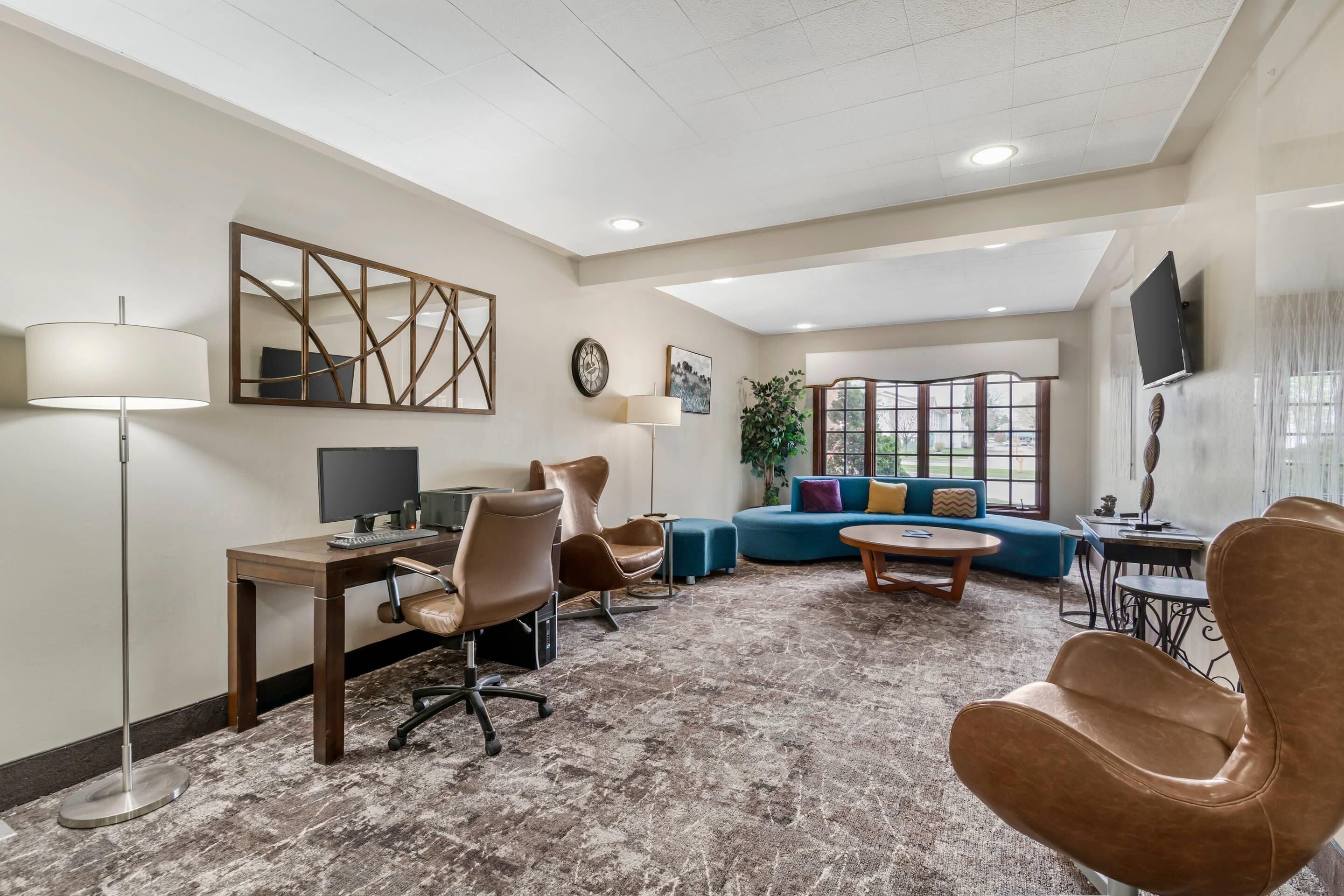 Un hall d’hôtel moderne avec un comptoir, des chaises, un canapé, une table basse, un téléviseur et une grande fenêtre.