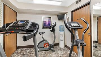 Un gimnasio con cintas de correr, elíptica y dispensador de agua.