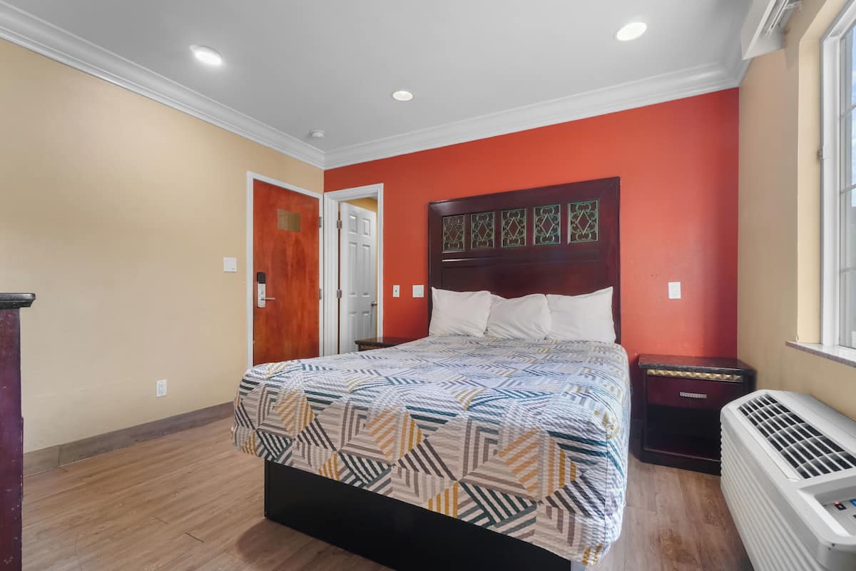 A bedroom with a bed, a nightstand, a heater, and a door.