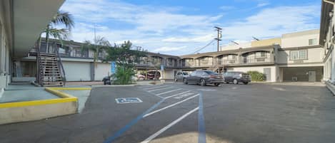 A parking lot with marked handicapped spaces, a staircase leading to a building, and several parked cars.