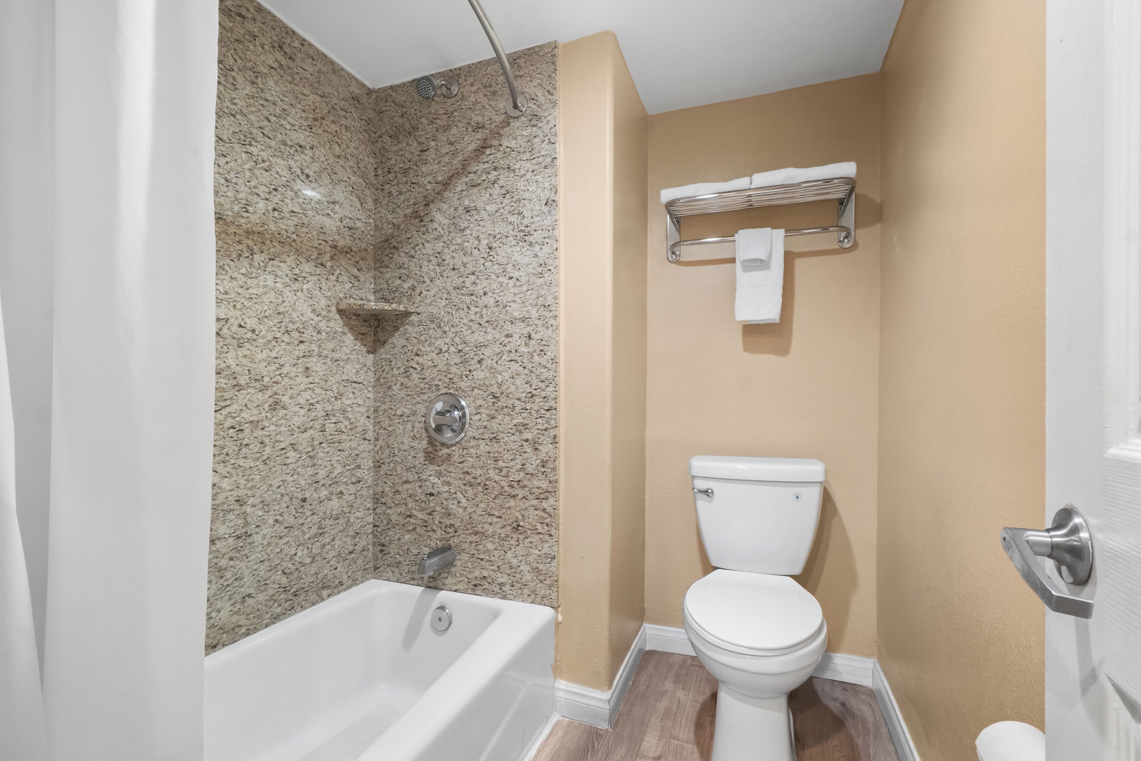 A bathroom with a bathtub, toilet, and a towel rack.
