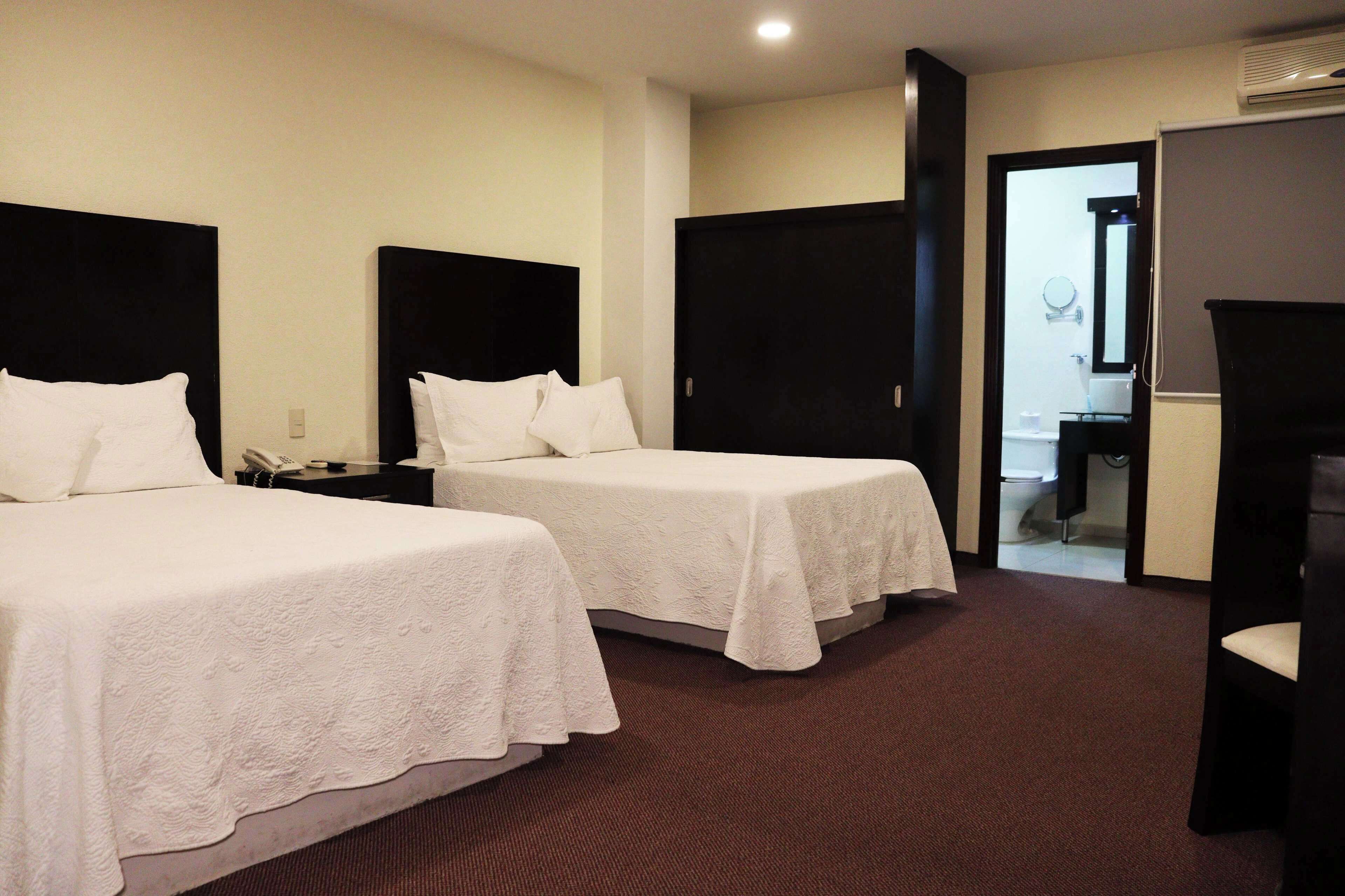 A hotel room with two beds, a bathroom, and a seating area.