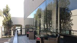 A modern outdoor seating area with wicker furniture and a glass railing overlooking a parking area.