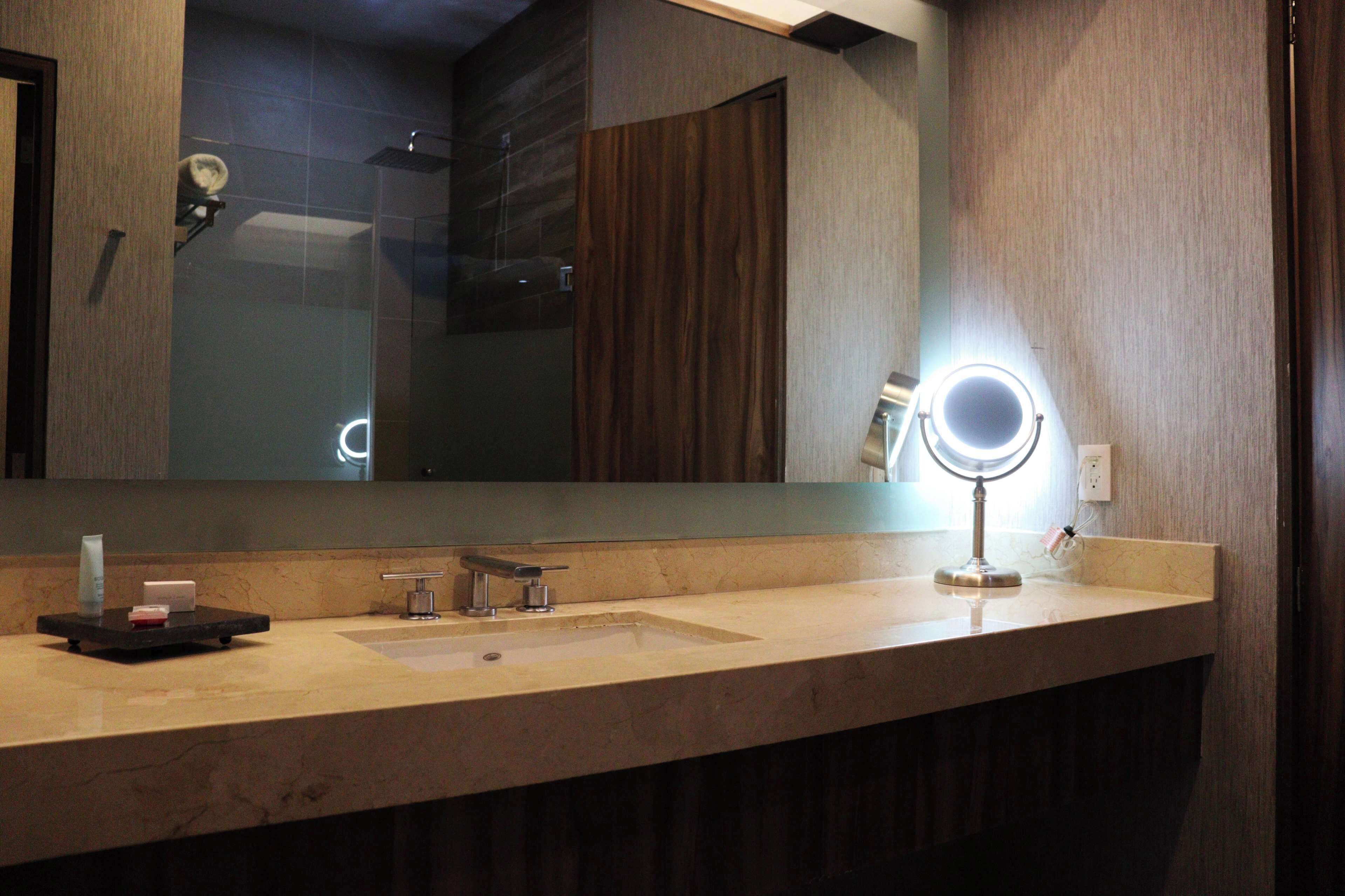 A bathroom with a large mirror, a sink, and a vanity area.