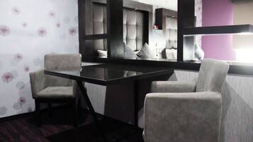 Una habitación con un espejo grande, dos sillas, una mesa de madera oscura y un papel tapiz estampado.