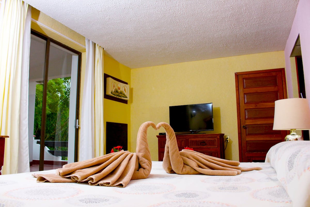A hotel room with a bed, a TV, and a door.