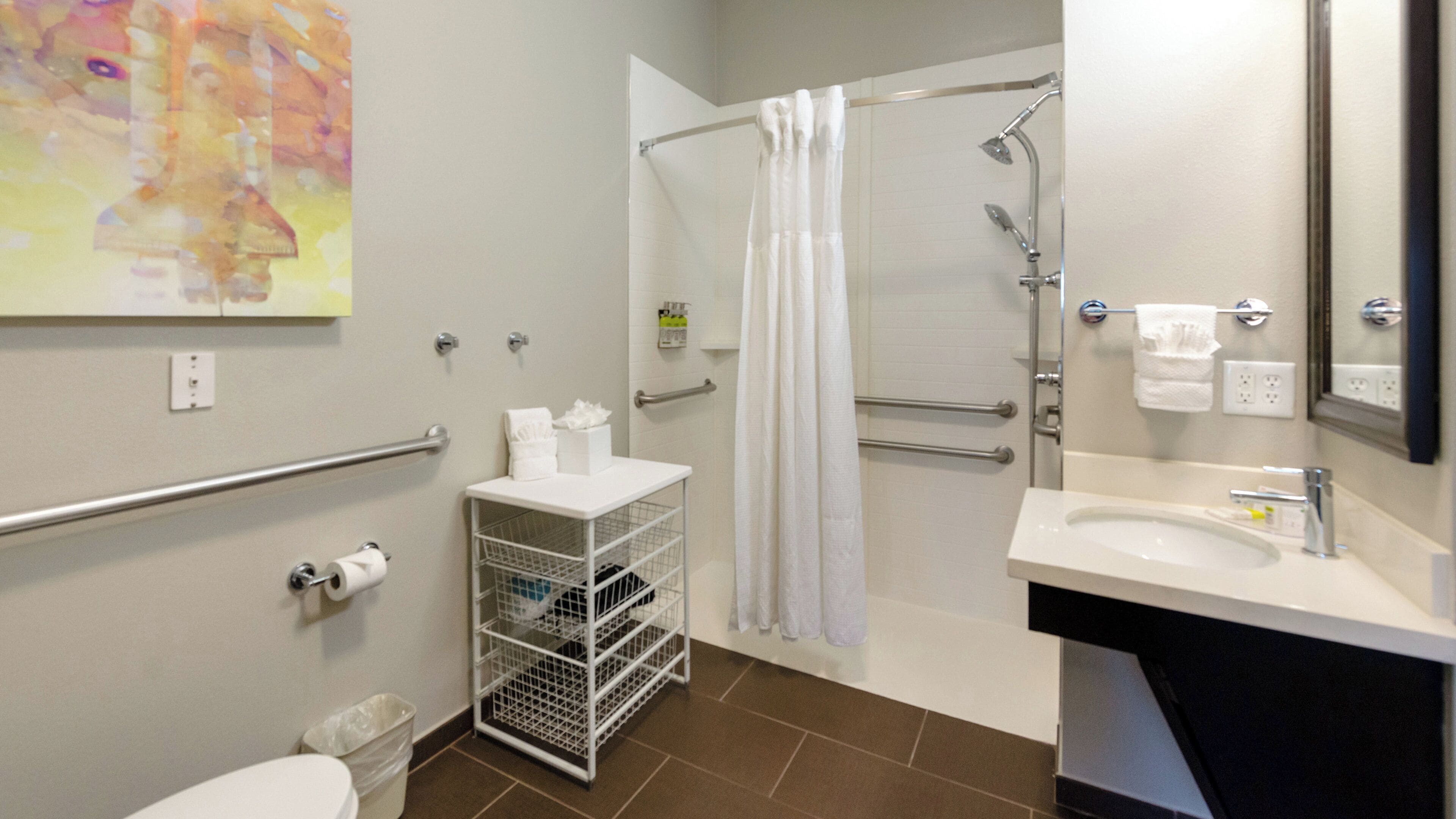 A bathroom with a shower, toilet, sink, and towel rack.