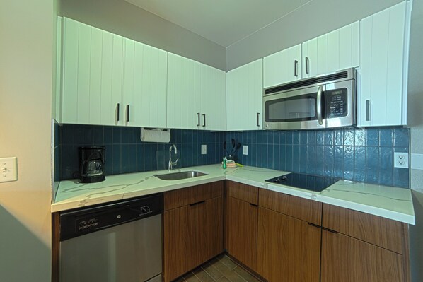 A kitchen with white cabinets, a dishwasher, a microwave, and a coffee maker.