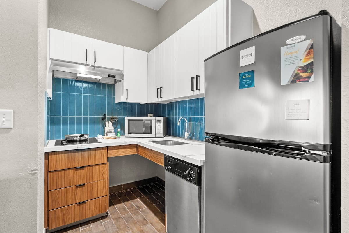 Una cocina moderna con armarios blancos, un refrigerador de acero inoxidable, un microondas y un lavavajillas.