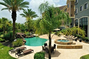 A pool area with lounge chairs, a hot tub, and palm trees. - Staybridge Suites Houston-Nasa/Clear Lake by IHG (Webster)