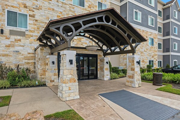A stone building with a covered entrance and a black door.